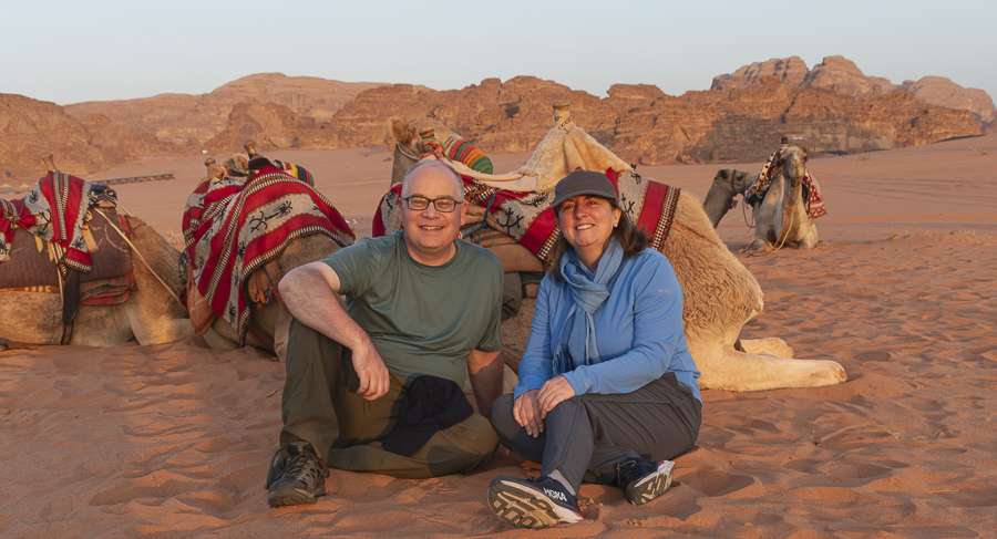 jordan-wadi-rum-sunset Brent and Missy sitting in sand with camels sitting down behind us at Wadi Rum in Jordan