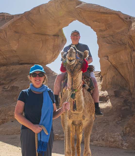 footer-wadi-rum Missy holding rope with Brent sitting on camel near an arch in Wadi Rum