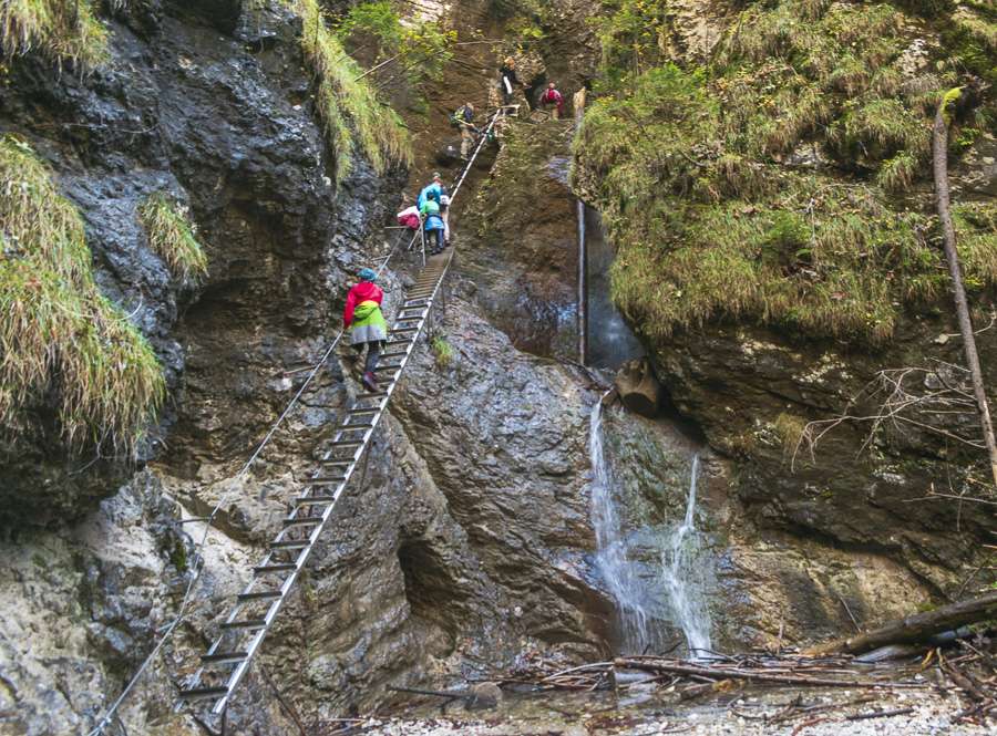 Climbers on steep ladder along waterfall of Sucha Bela hike at Slovak Paradise National Park